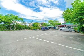 Un parking avec des voitures, des arbres et des bâtiments en arrière-plan.