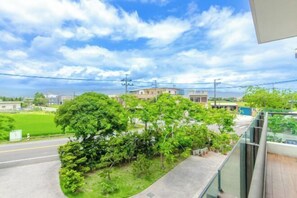 A residential area with a road, greenery, and buildings in the background.