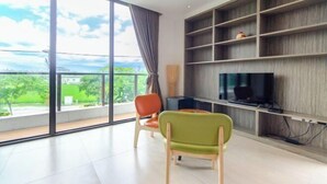 A modern living room with a large window, a flat-screen TV, and a bookshelf. - Colorful Fish Cottage (Yilan)