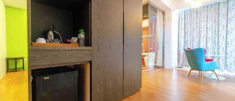 Uma sala de estar moderna com área de cozinha integrada, uma cadeira azul e piso de madeira.