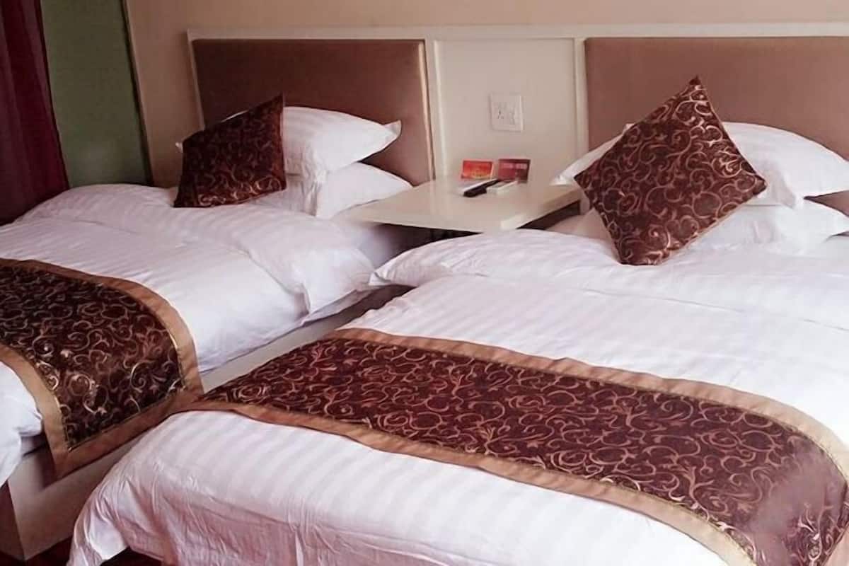 Habitación de hotel con dos camas, cada una con cabecera, mesita de noche y colcha estampada.