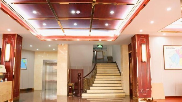 A hotel lobby with a marble floor, a staircase, and a reception desk. - Baiyun Hotel (Shaoxing)