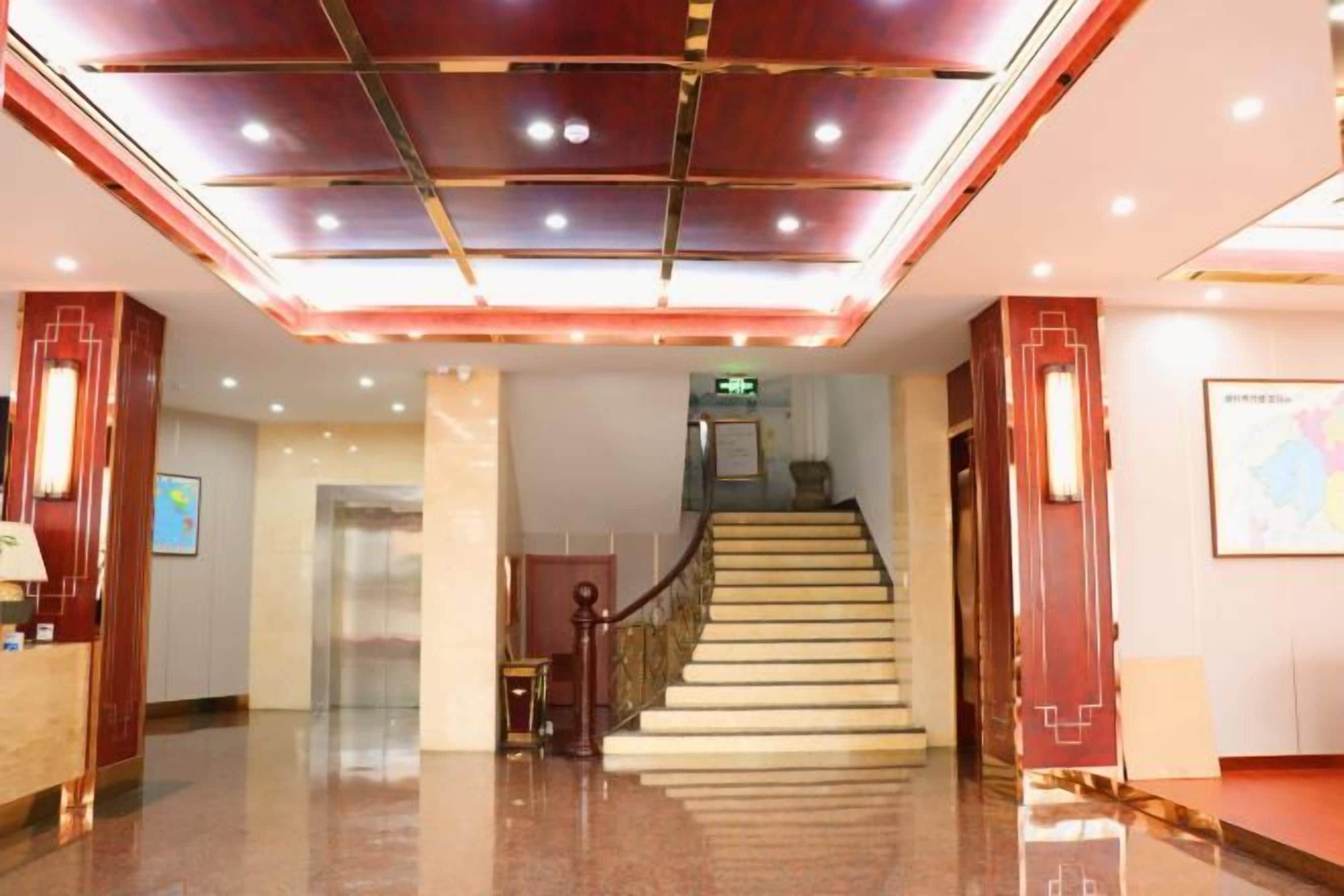 A hotel lobby with a staircase, a reception desk, and a map on the wall.