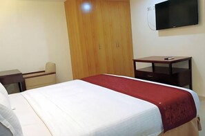 Een hotelkamer met een bed, een bureau, een kledingkast en een televisie.