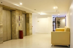 A hotel lobby with a reception desk, a yellow sofa, and a trash bin. - Chinatown Lai Lai Hotel Manila (City of Manila)
