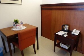 A hotel room with a wooden desk, a chair, a small table with a kettle and a phone, and a wooden wardrobe. - Chinatown Lai Lai Hotel Manila (City of Manila)
