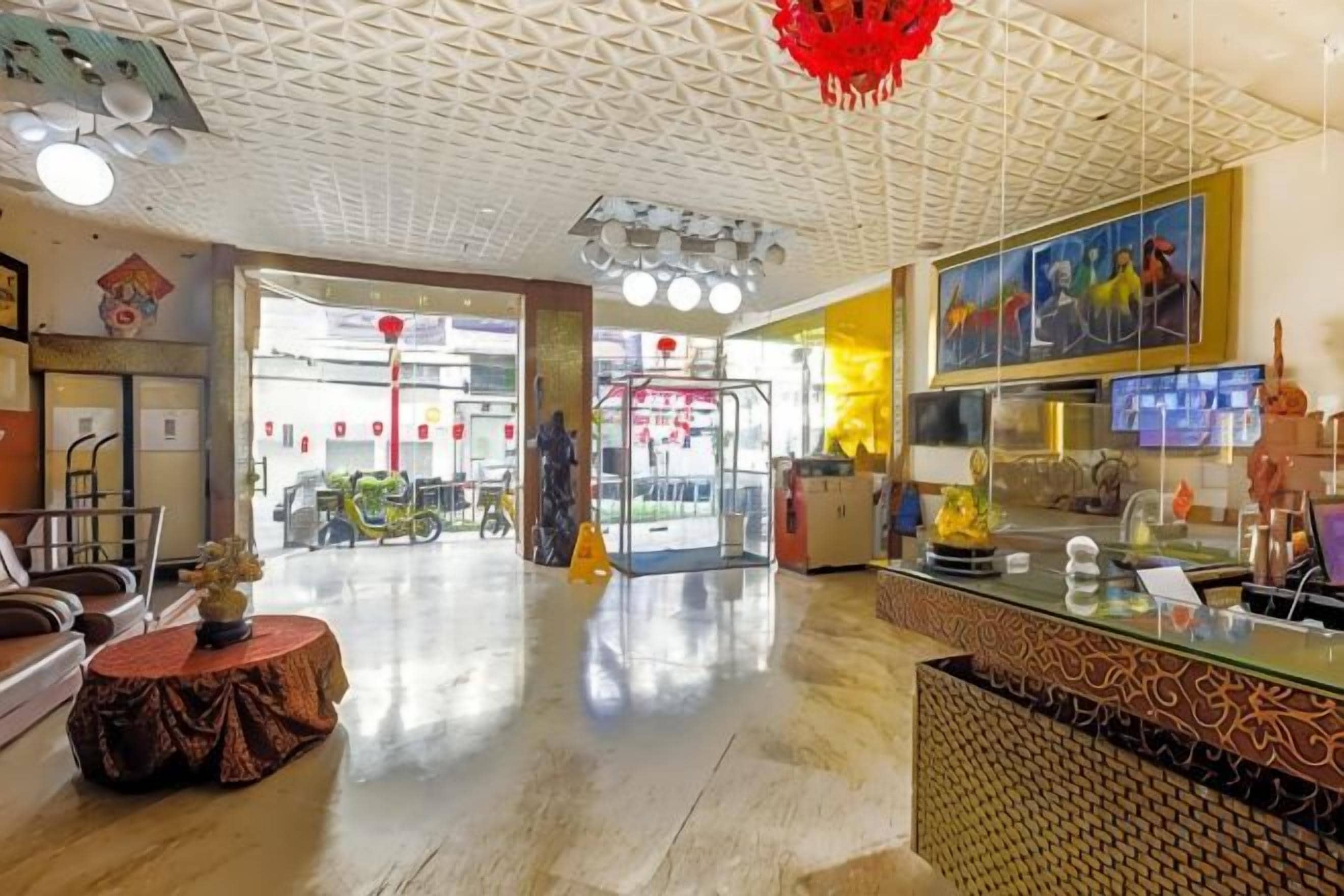 Een hotel lobby met een receptiebalie, een zithoek en een glazen displaykast.