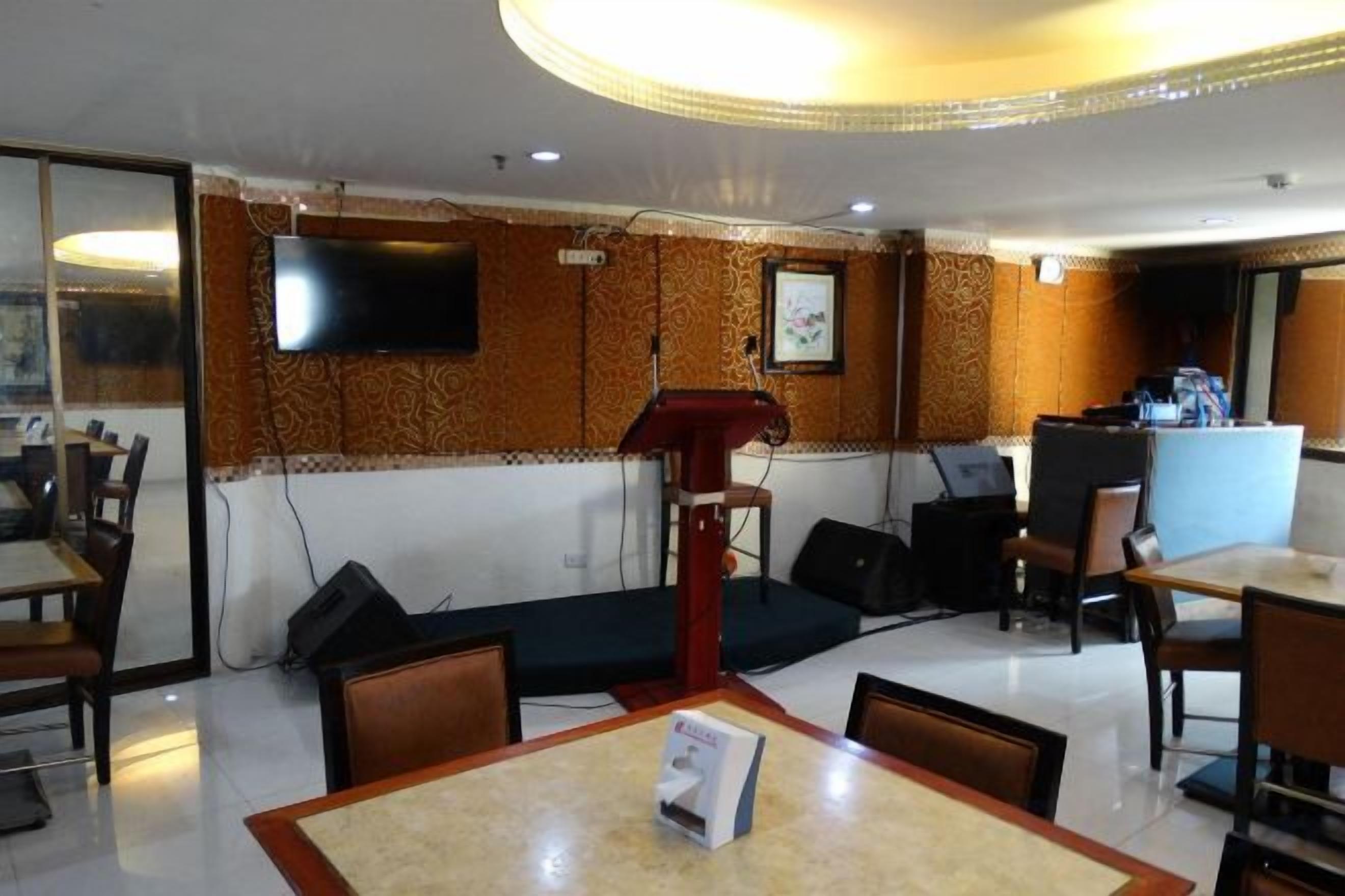 A hotel lobby with a reception desk, seating area, and a television mounted on the wall.