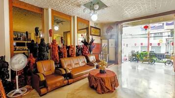 A spacious living area with a brown leather sofa, a round table, and a fan.