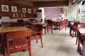 A restaurant interior with wooden tables and chairs, a tiled floor, and a menu board in the background. - Chinatown Lai Lai Hotel Manila (City of Manila)