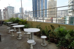 Outdoor seating with tables and potted plants on a rooftop with a city view. - Chinatown Lai Lai Hotel Manila (City of Manila)