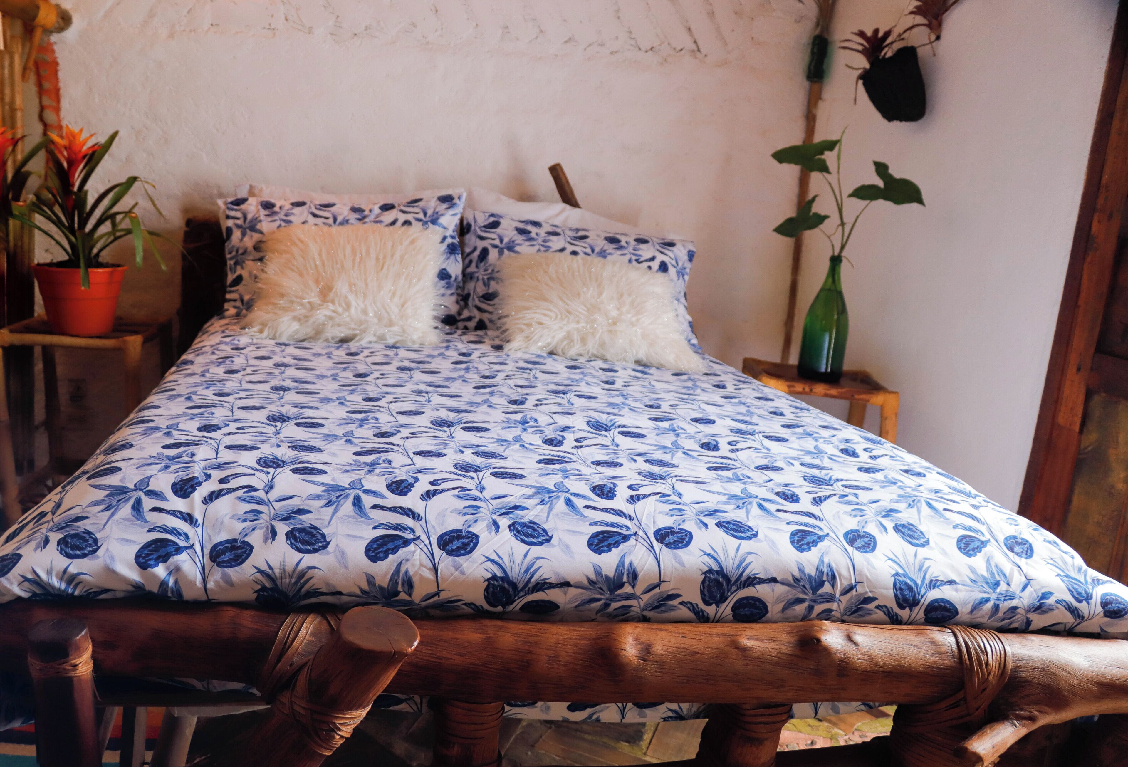 A bed with a blue floral bedspread, two white fluffy pillows, and a wooden headboard.