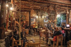 Un interior rústico con muebles de madera, un músico tocando y clientes sentados en mesas.