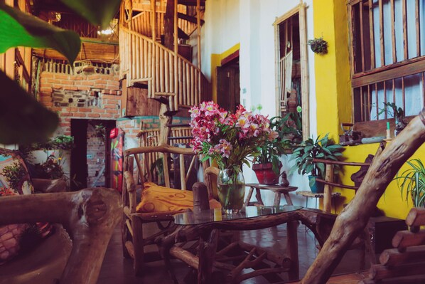 A rustic interior with a wooden staircase, a brick fireplace, and a yellow wall.