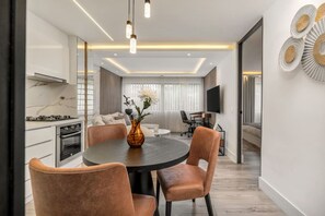 A modern kitchen with a dining area, a round table with chairs, and a vase with flowers.