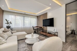 A modern living room with a sofa, a coffee table, a TV, and a desk area. - delite* Elite Heaven:Luxurious1Bed+1bath (Medellín)