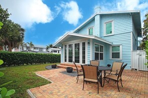 Una casa con patio, un espacio de estar techado al aire libre y un césped bien cuidado.