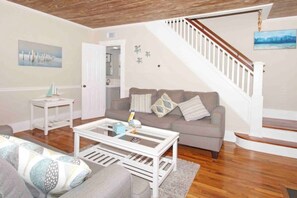 Una sala de estar con un sofá, una mesa de centro y una escalera.