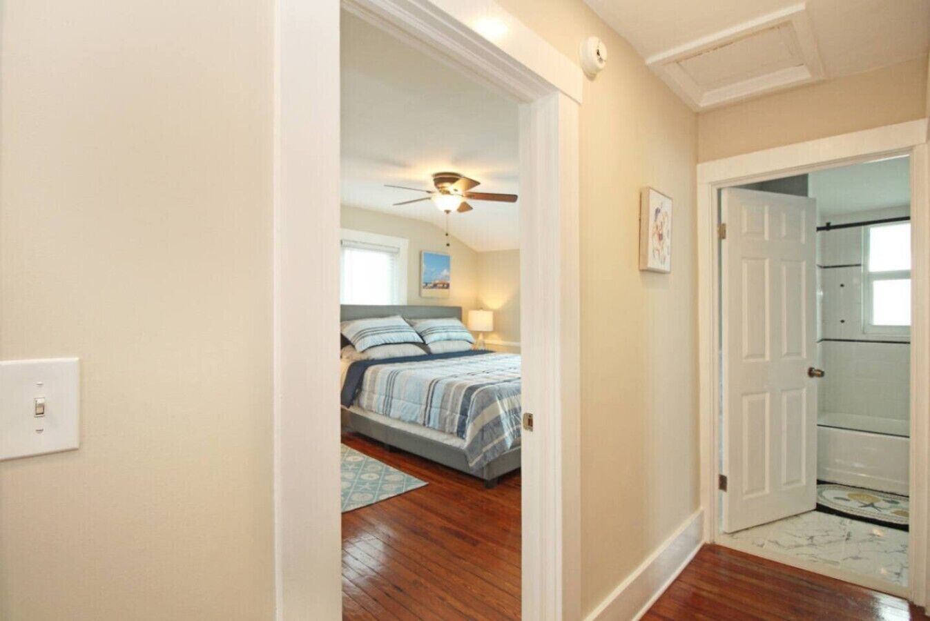 A bedroom with a bed, a ceiling fan, and a door leading to another room.