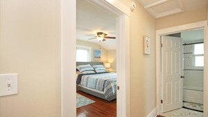 Un dormitorio con cama, ventilador de techo y puerta que da a otra habitación.