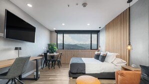 A modern bedroom with a large bed, a desk, and a view of mountains through the window. - ✨Perfect Studio✨View+COwork+NewBuilding+FastWIFI (Medellín)