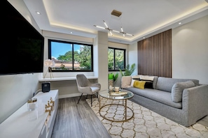 A modern living room with a sofa, a coffee table, a TV, and a large window. - High End Apartment 1 BD  1 BA Views Ac Malls (Medellín)