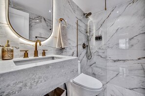 A modern bathroom with a marble sink, gold fixtures, and a handheld showerhead. - High End Apartment 1 BD  1 BA Views Ac Malls (Medellín)