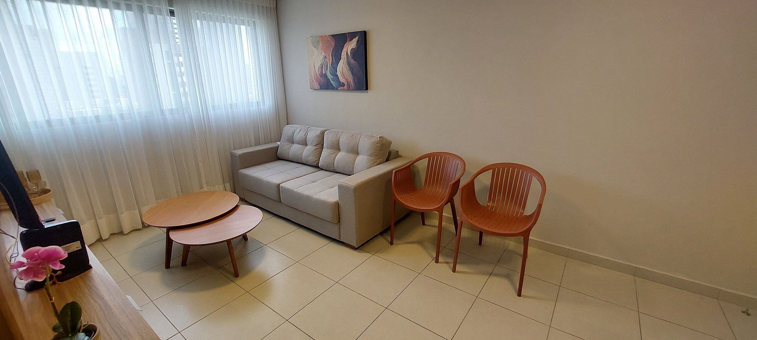Un salon comprenant un canapé, deux tables en bois et deux chaises en plastique.