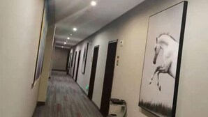 A hotel hallway with doors on one side and a large horse painting on the wall. - Junyi Chain Hotel (Tianmen baoan palza Store) (Tianmen)