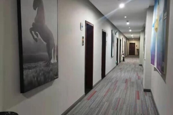 A hotel corridor with doors, a patterned carpet, and artwork on the walls. - Junyi Chain Hotel (Tianmen baoan palza Store) (Tianmen)