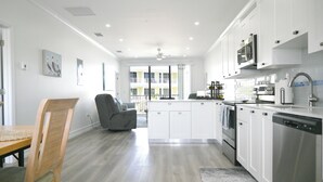 Cuina moderna amb armaris blancs, electrodomèstics d'acer inoxidable i una catifa gris.