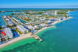 An aerial view of a coastal resort with multiple buildings, a beach, and clear turquoise waters. - *New Luxury Beachfront* Kokomo Views Beach,Pool (Key Colony Beach)