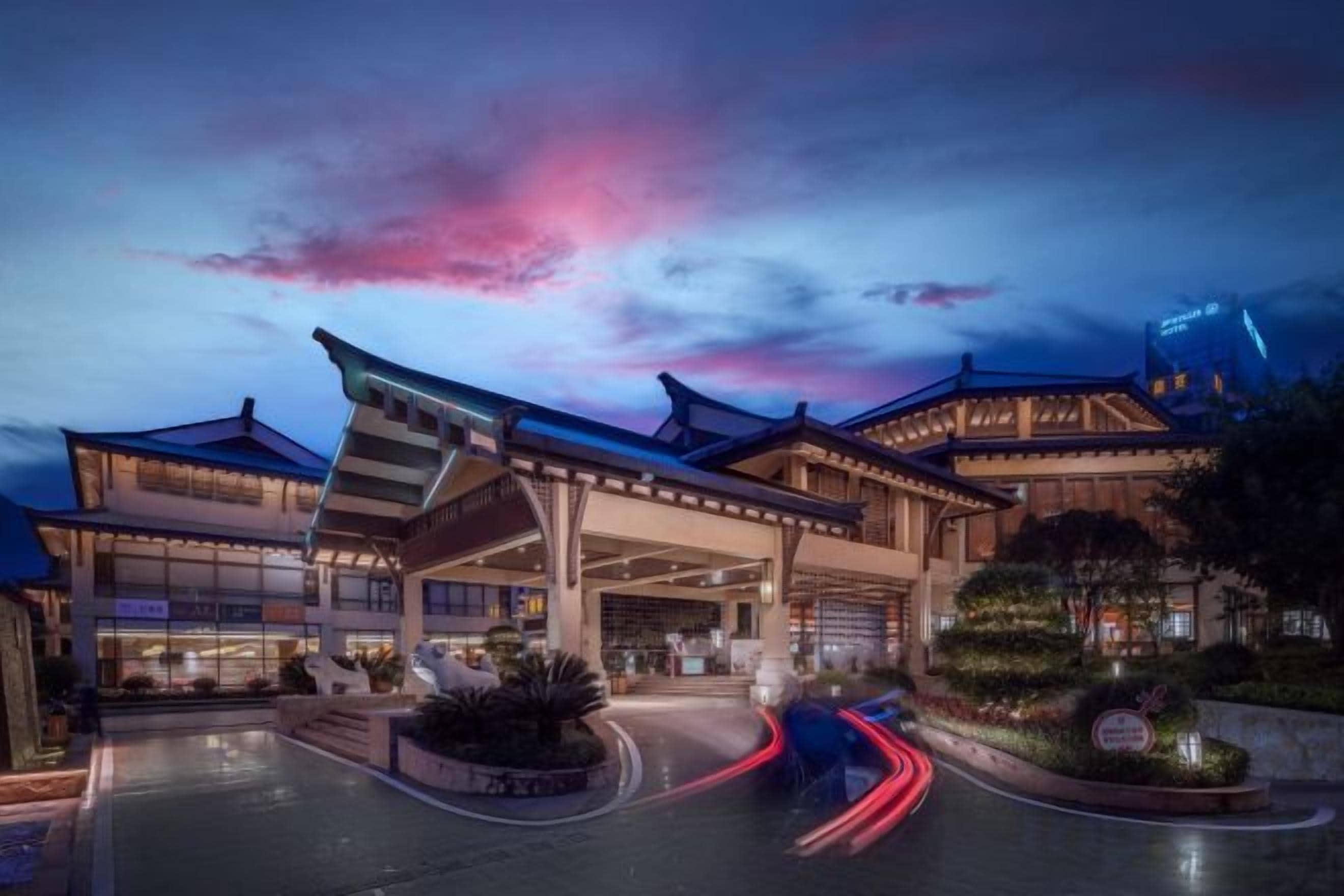 A hotel with a traditional architectural style, featuring a large entrance and a well-lit driveway.