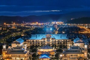 A large hotel with multiple buildings, featuring a prominent central structure with a large umbrella and a smaller building to the left. - JP Hyllis Hotel (Chuxiong City)