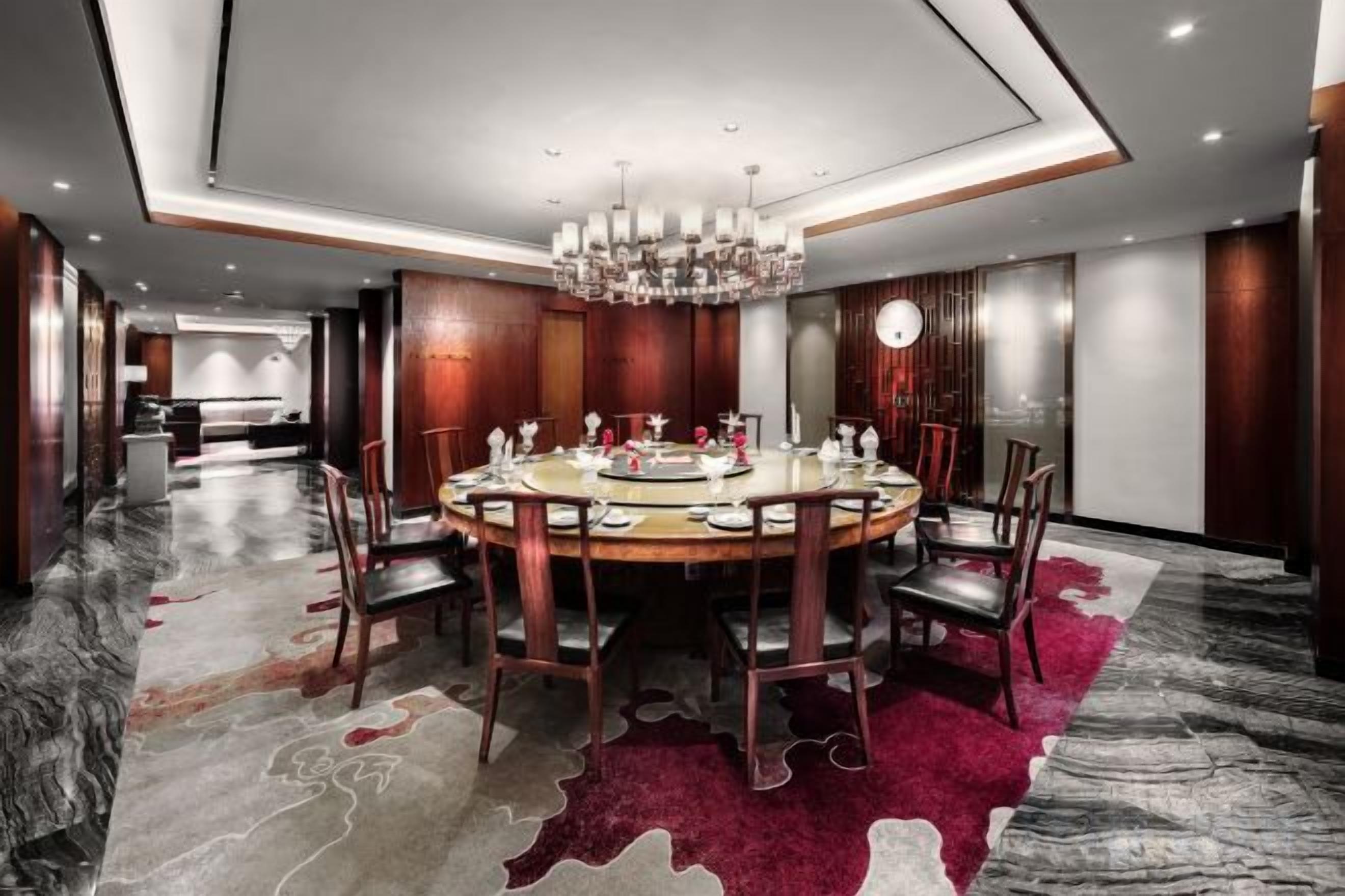 A modern dining area with a round table, chairs, and a chandelier.