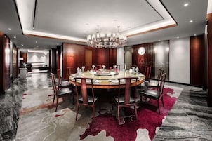 A modern dining area with a round table, chairs, and a chandelier.