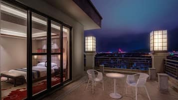 A balcony with a bed, two chairs, and a table.