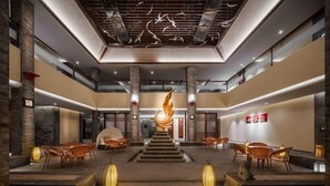 Un hall d’entrée spacieux avec un escalier central, un éclairage moderne et des coins salon.
