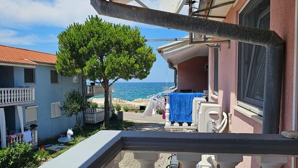 A balcony with a view of the sea, a tree, and a building with a balcony. - Apartment Furdi - Two Bedroom Apartment with Terrace (Zaton)