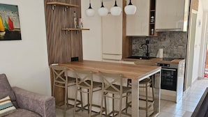 A modern kitchen with a wooden island, bar stools, and pendant lighting. - Apartment Furdi - Two Bedroom Apartment with Terrace (Zaton)