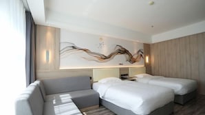 A modern hotel room with a sofa, two beds, a large abstract wall art, and a wooden panel wall. - Tianjing Hotel (Shenyang)