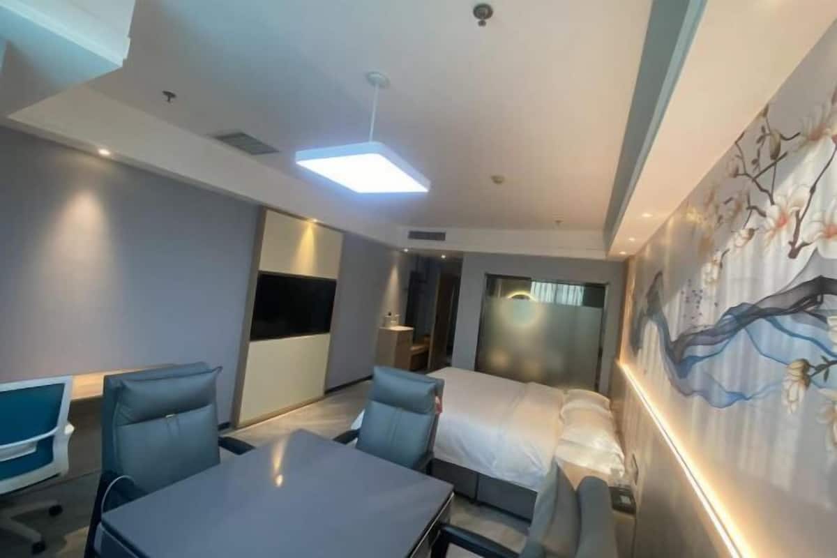 Quarto de hotel moderno com cama, escrivaninha e uma cadeira.