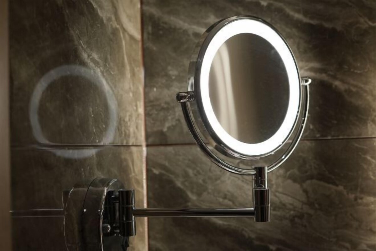 A bathroom vanity with a mirror and a chrome faucet.