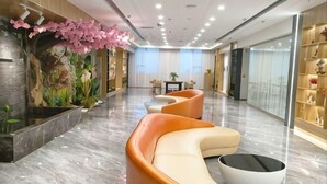 A modern lobby with a reception desk, seating area, and decorative plants. - Tianjing Hotel (Shenyang)