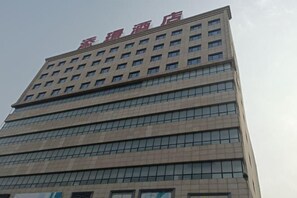 A tall hotel building with a modern design, featuring multiple floors and a prominent signage at the top.