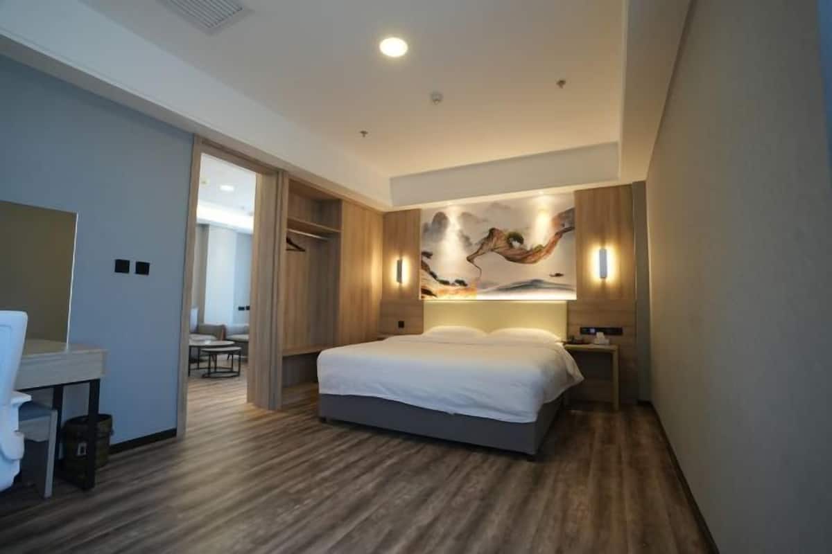 Quarto de hotel moderno com cama, mesa de cabeceira e uma obra de arte pendurada na parede.