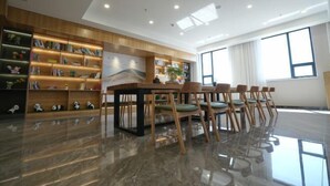 A modern library with a large table and chairs, surrounded by bookshelves. - Tianjing Hotel (Shenyang)