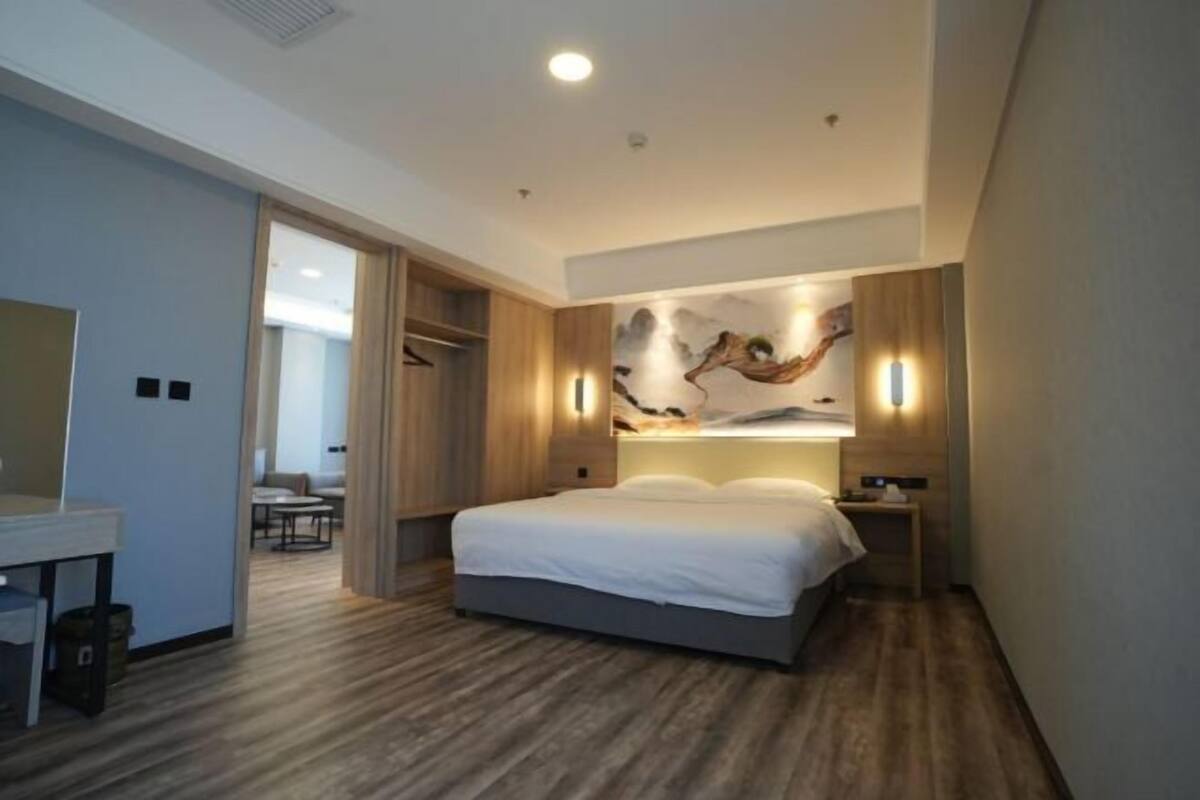 Quarto de hotel moderno com uma cama grande, uma mesa de trabalho e um banheiro.