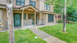 A two-story house with a stone foundation, a covered porch, and a well-maintained lawn.