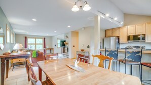 A spacious dining area with a long wooden table and chairs, a kitchen with wooden cabinets and modern appliances, and a cozy seating area with a fireplace.